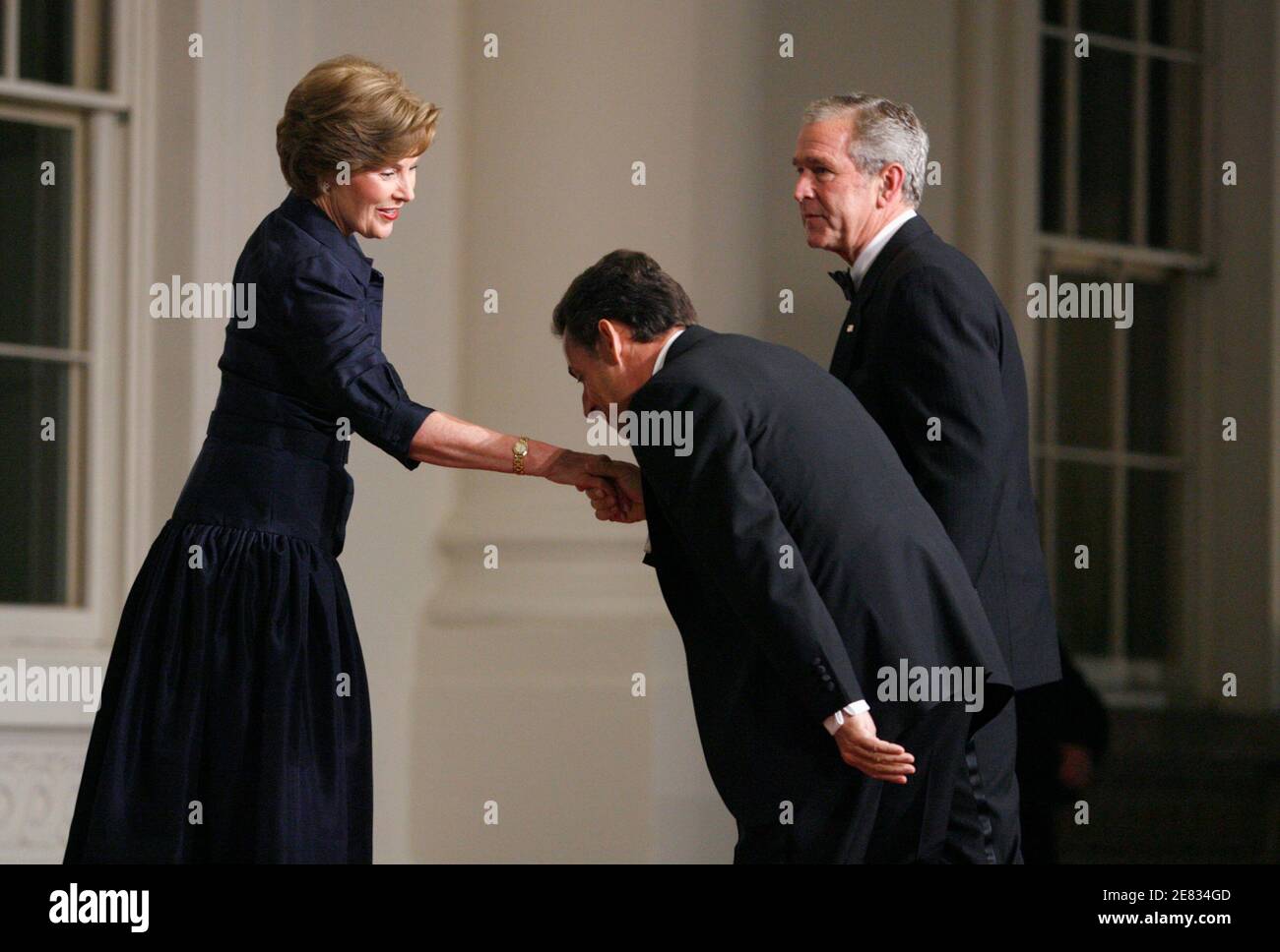 French President Nicolas Sarkozy (C) kisses the hand of First Lady Laura  Bush as U.S. President George W. Bush looks on upon his arrival for dinner  at the White House in Washington