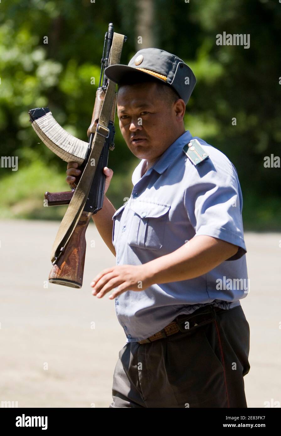 A Kyrgyz police officer walks with his Kalashnikov rifle in the city of Osh June 29, 2010.  REUTERS/Shamil Zhumatov  (KYRGYZSTAN - Tags: POLITICS) Stock Photo