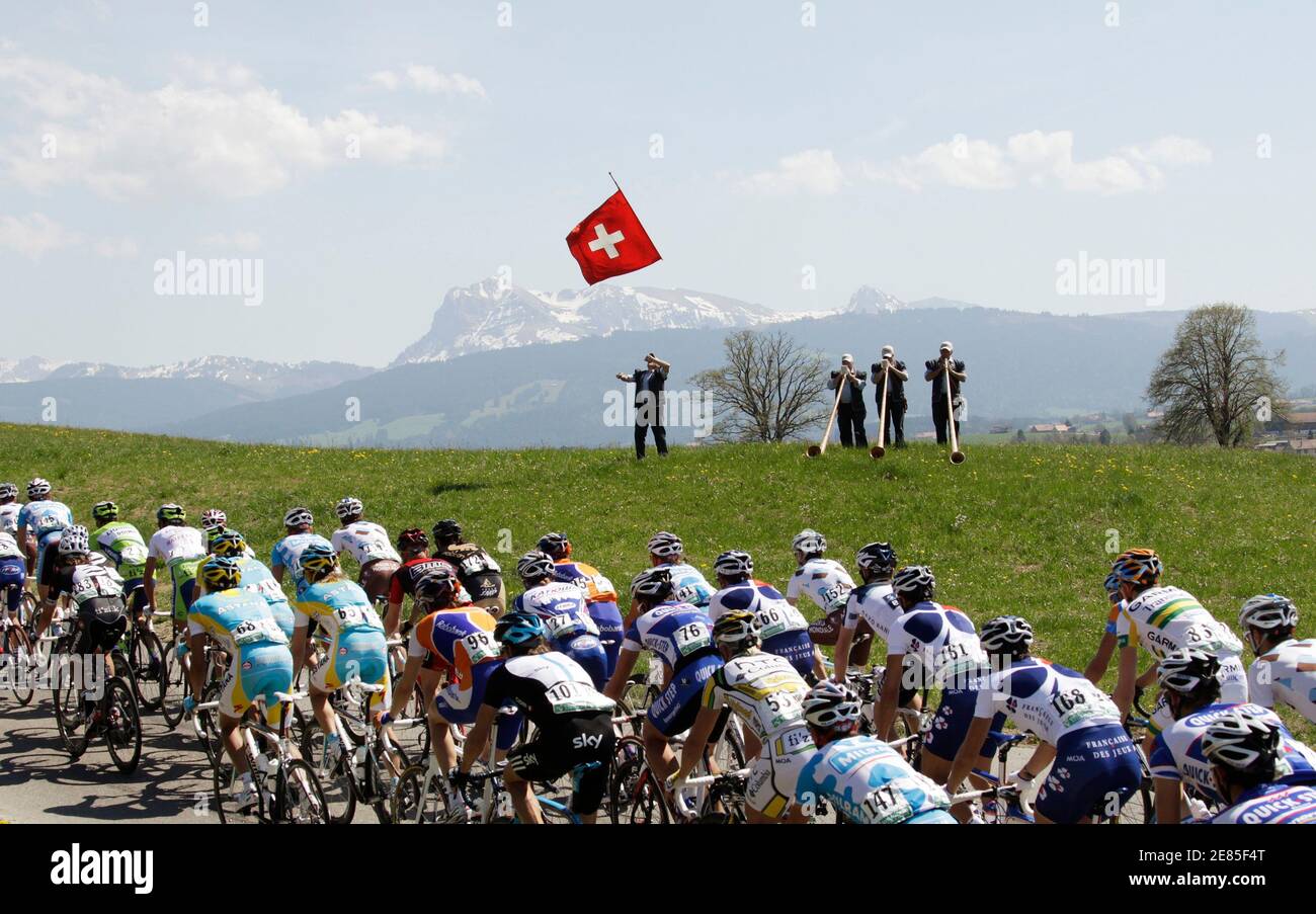 A pack of riders cycle past alphorn blowers and a man waving a Swiss flag  during the second stage of the Tour de Romandie cycling race in Mezieres  April 29, 2010. REUTERS/Denis