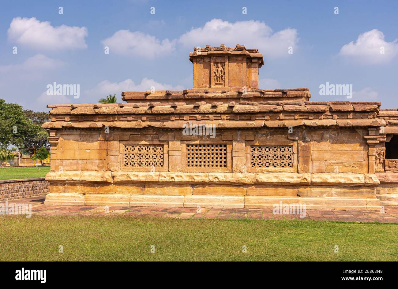 Aihole, Karnataka, India - November 7, 2013: Lad Khan or Chalukya Shiva Temple. Side veiw on brown stone building under blue cloudscape and green lawn Stock Photo