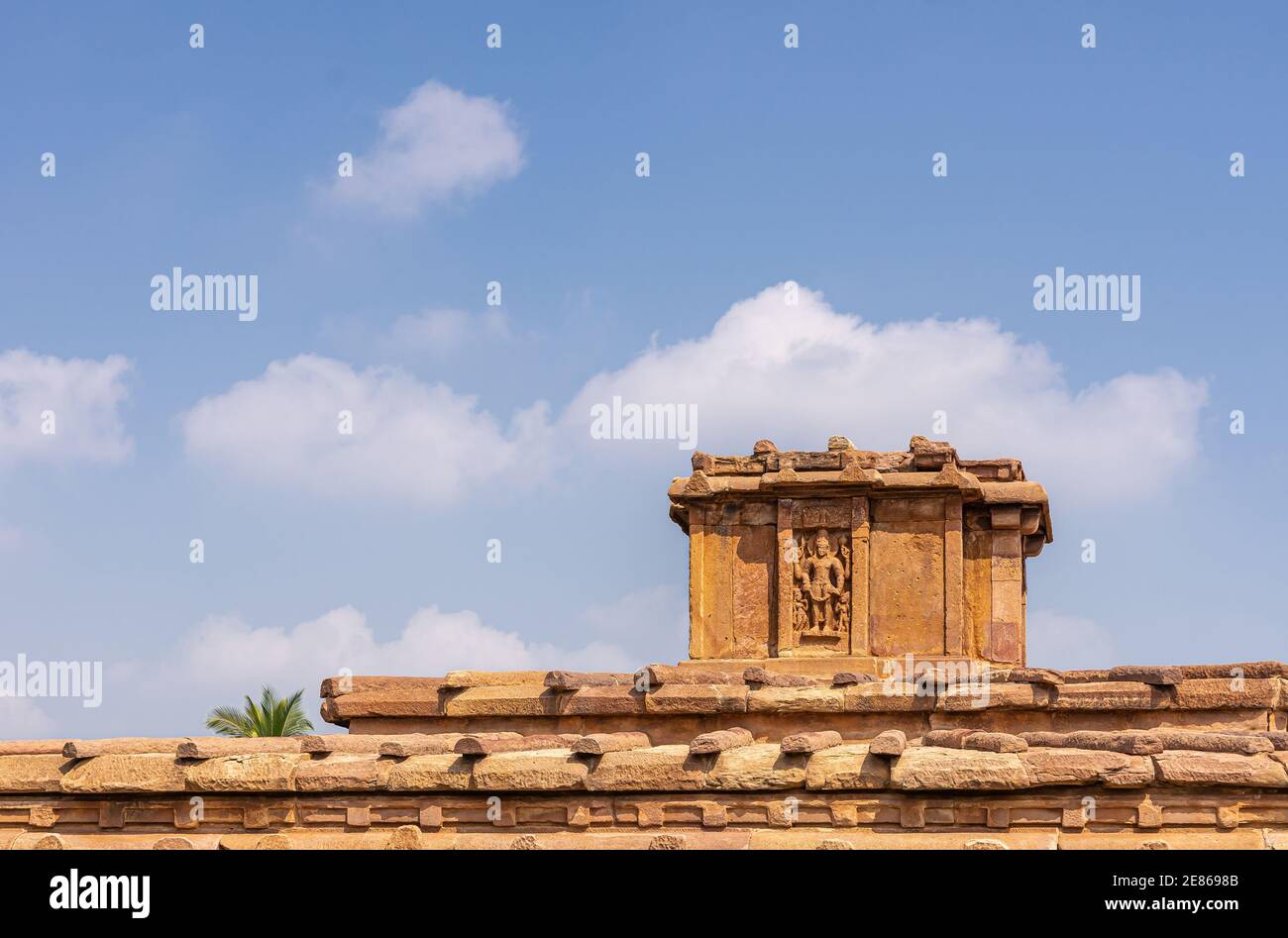 Aihole, Karnataka, India - November 7, 2013: Lad Khan or Chalukya Shiva Temple. Top statue of Shiva on brown stone building under blue cloudscape. Stock Photo