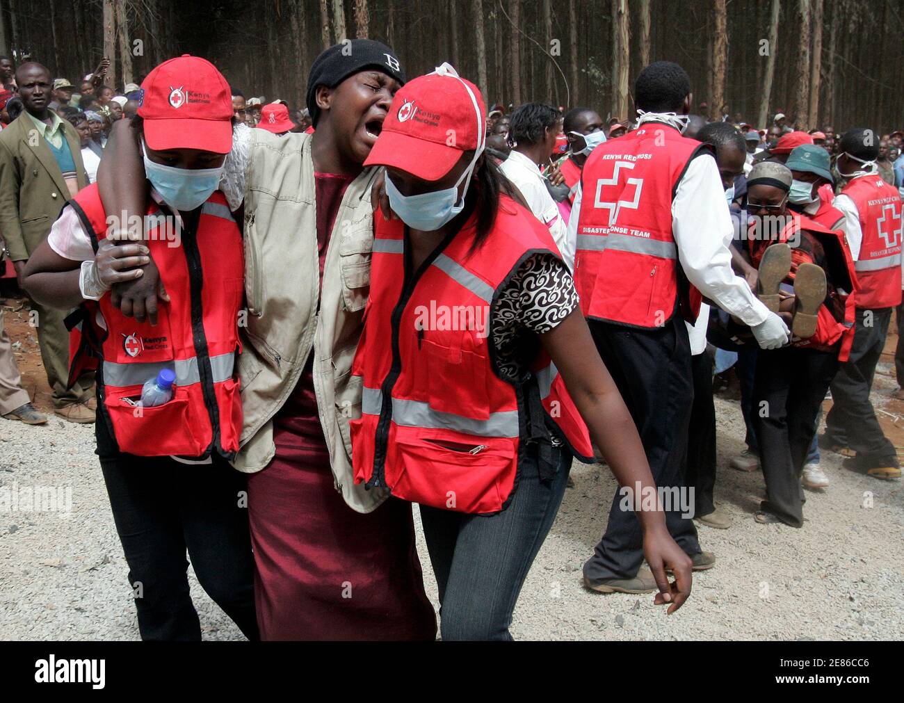 Kenya Red Cross workers carry a mourner during the mass burial of 89 people  killed in a fire a fortnight ago in Molo town, about 196 km (122 miles)  from the capital