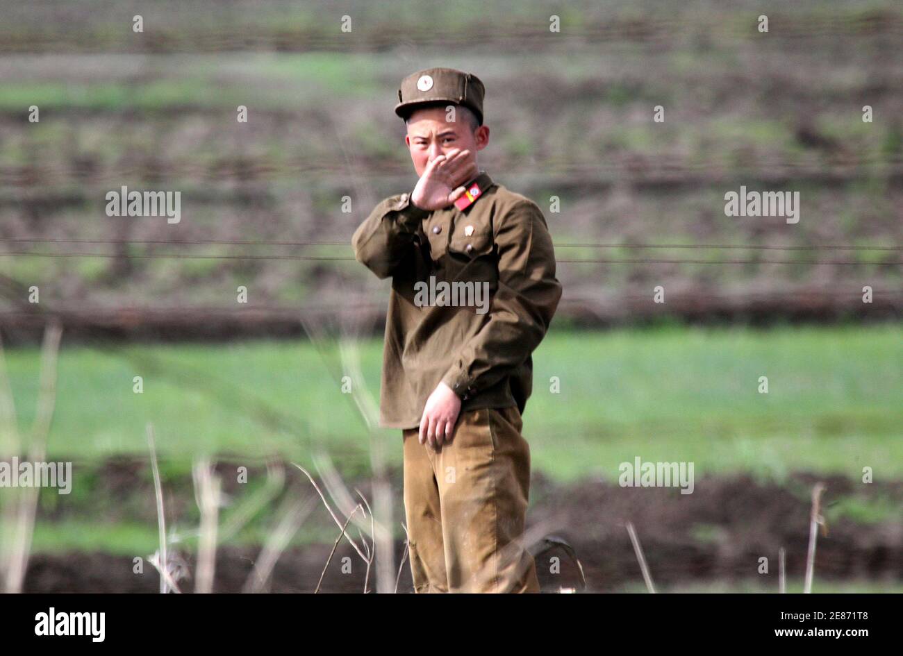A North Korean soldier gestures while guarding the banks of the Yalu River near the North Korean town of Sinuiju May 25, 2010. North Korean leader Kim Jong-il has told his military it may have to go to war but only if the South attacks first, according to the South Korea-based news agency Yonhap that monitors the hermit state.     REUTERS/Jacky Chen (NORTH KOREA - Tags: MILITARY POLITICS) Stock Photo