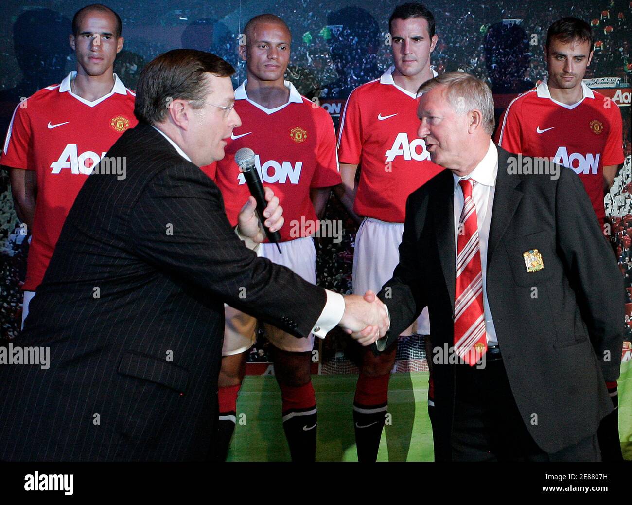 Aon Corporation Chief Executive Greg Case (L) shakes hands with Manchester  United manager Sir Alex Ferguson as players (rear, L-R) Gabriel Obertan,  Wes Brown, John O'Shea and Dimitar Berbatov wear their new