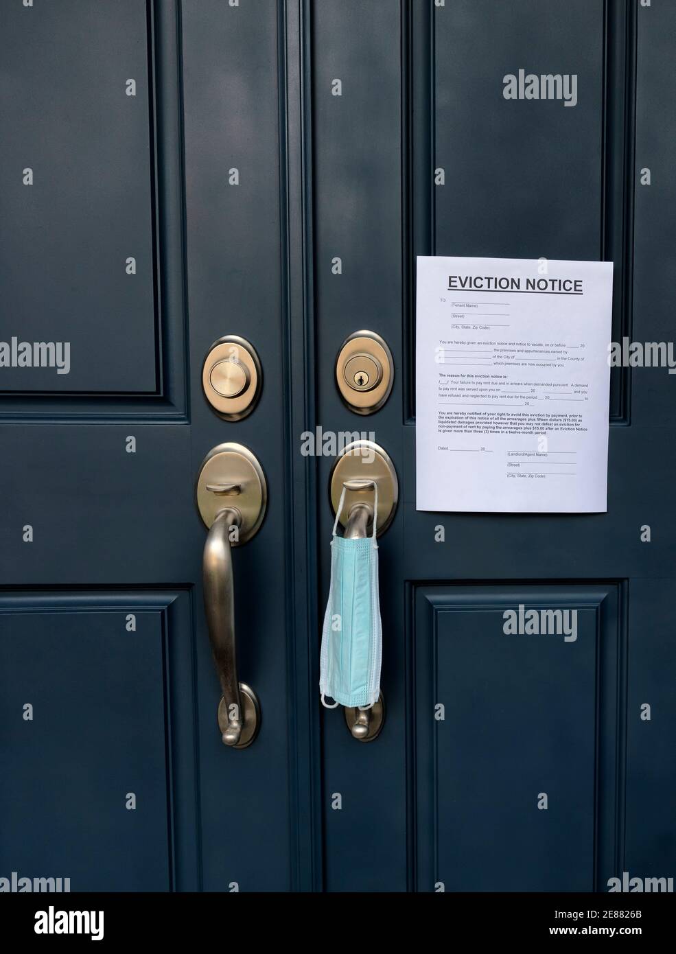 Home front door with eviction notice and facemask for renter in default during Covid 19 pandemic Stock Photo