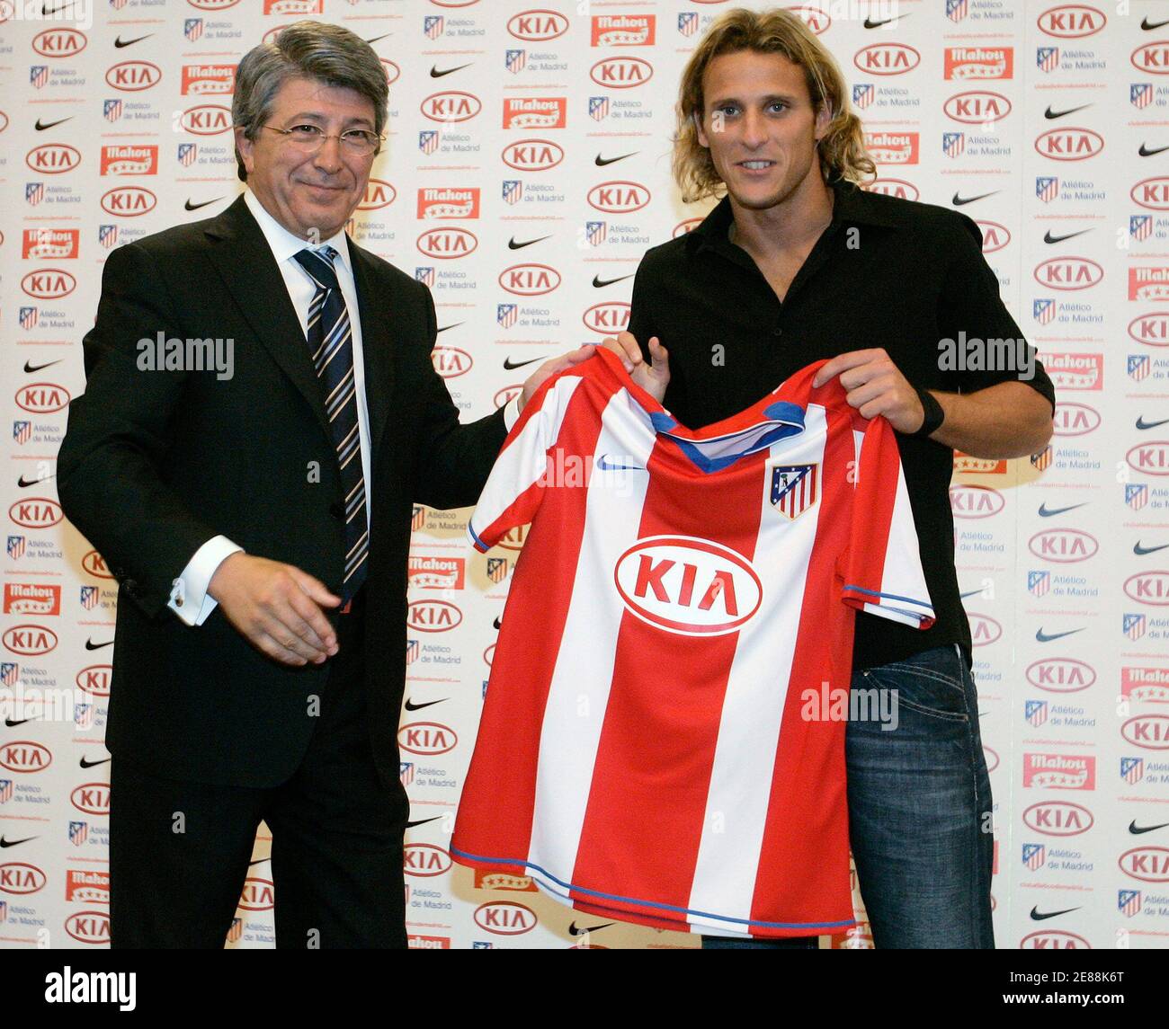 Diego Forlan (R) of Uruguay, who was newly signed by Atletico Madrid, holds  the Atletico Madrid shirt with the team's President Enrique Cerezo during  his presentation at the Vicente Calderon stadium in