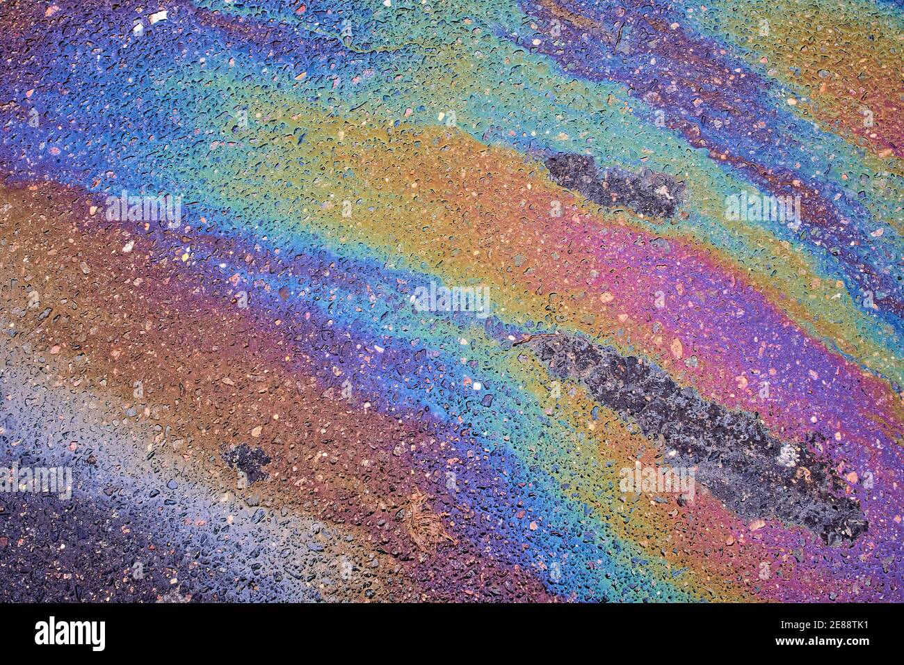 Gas stain on wet asphalt caused by a leak under a car or truck Stock