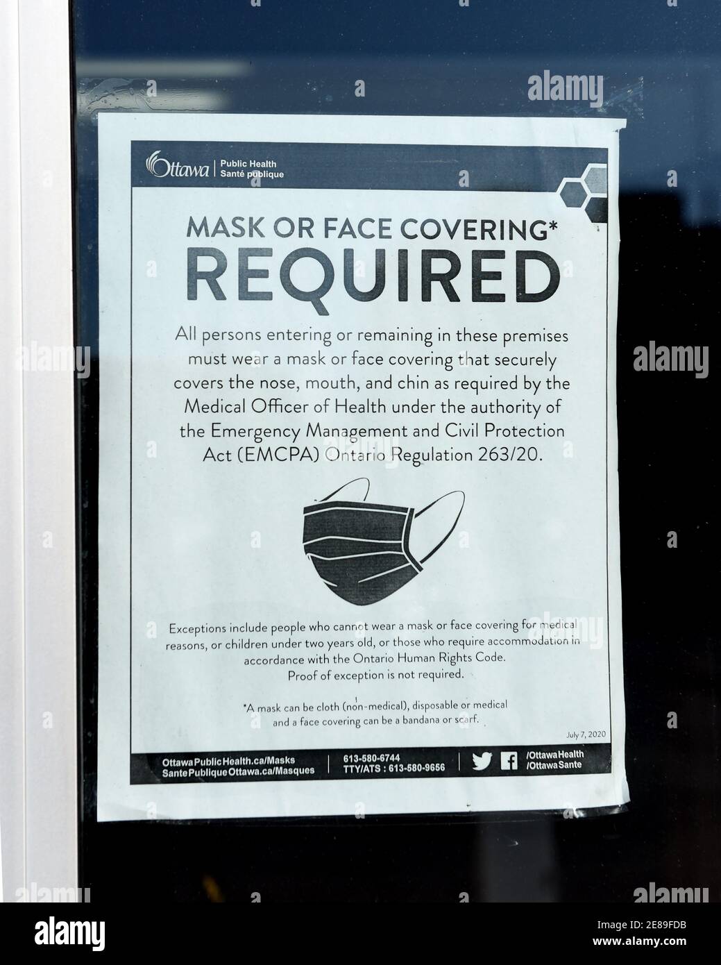 Ottawa, Canada - January 30, 2021: Sign on the door on store window stating the details of the mask bylaw created by Ottawa Public Health. Stock Photo