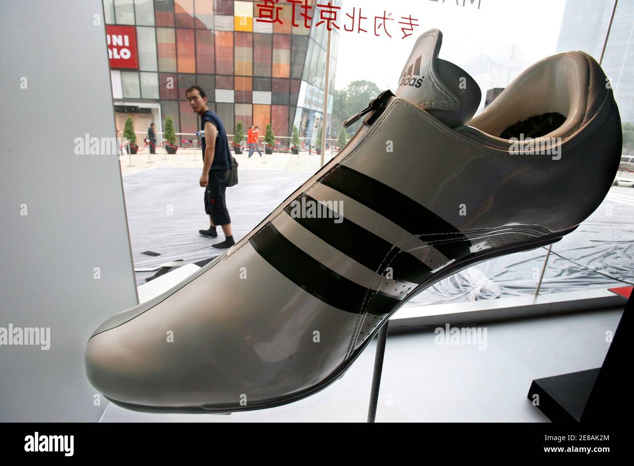 A man looks at a giant shoe display at the new and world's largest Adidas  Brand Center store in Beijing July 4, 2008. Adidas will open its world's  largest Adidas store with
