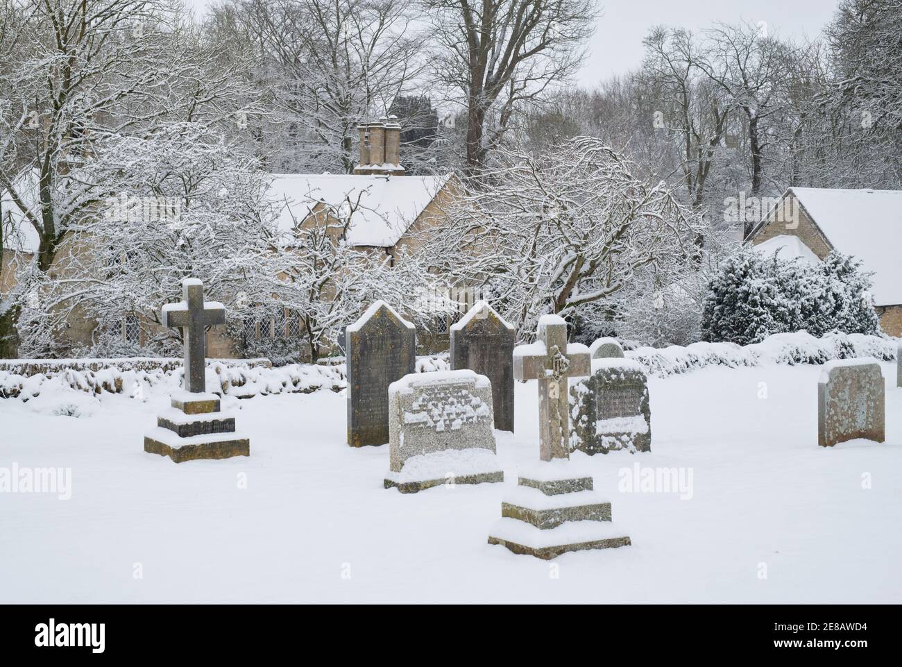 Grave stones in St Marys churchyard in the snow. Swinbrook, Cotswolds, Oxfordshire, England Stock Photo
