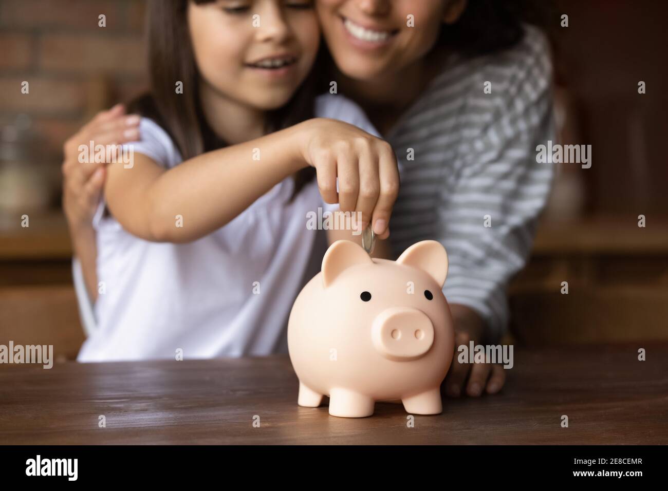 Close up mother and daughter putting coin into piggy bank Stock Photo ...