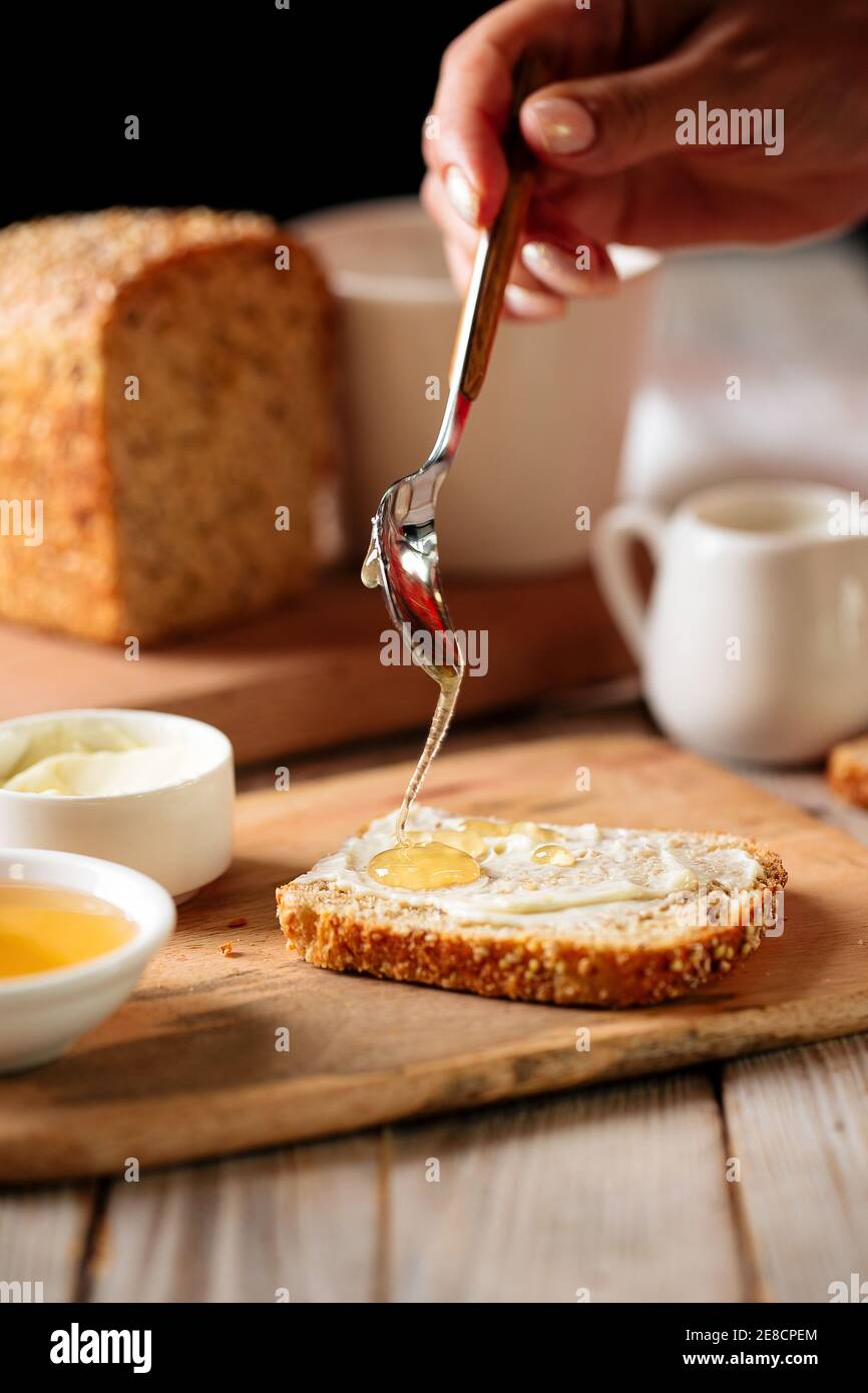 Side view on spreading bread slice with honey Stock Photo Alamy