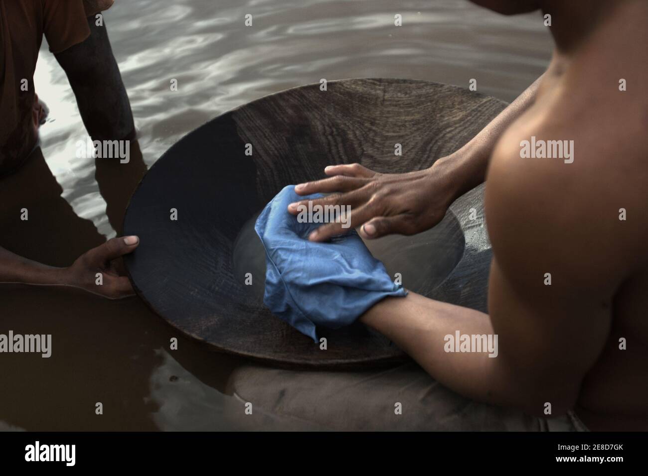 Gold miners processing gold particles with mercury amalgamation on a pond in a small-scale gold mining area in Hampalit, Katingan regency, Central Kalimantan province, Indonesia. Stock Photo