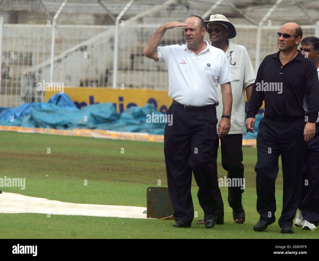 Umpires Daryl Harper (L) and Mark Benson (R) accompanied by Indian groundsmen inspect the ground at the M.A.Chidambram stadium in Chennai December 3, 2005. The second day's play of the first test match between India and Sri Lanka was called off due to wet ground conditions caused by rains. India and Sri Lanka will play a three test match series. REUTERS/Arko Datta Stock Photo