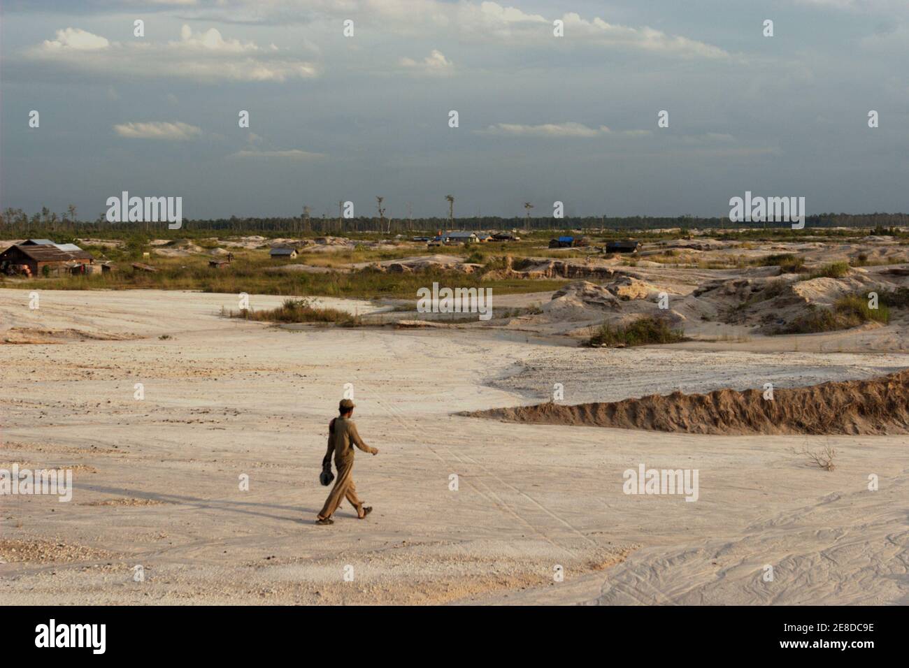 A gold miner walking down the sandy landscape of the small-scale gold mining area in Hampalit, Katingan regency, Central Kalimantan province, Indonesia. Stock Photo
