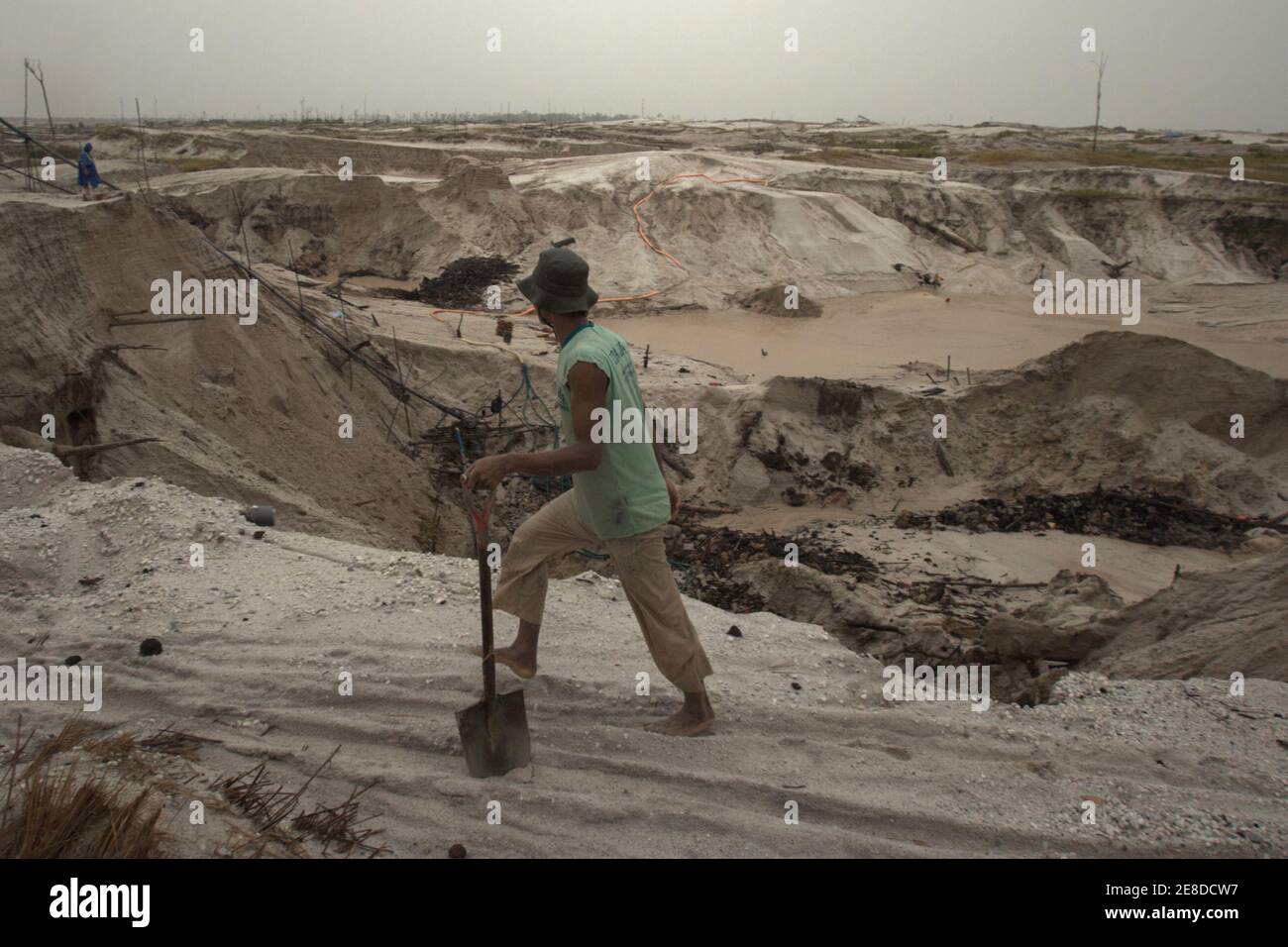 A gold miner walking on the sandy landscape of the small-scale gold mining area in Hampalit, Katingan regency, Central Kalimantan province, Indonesia. Stock Photo