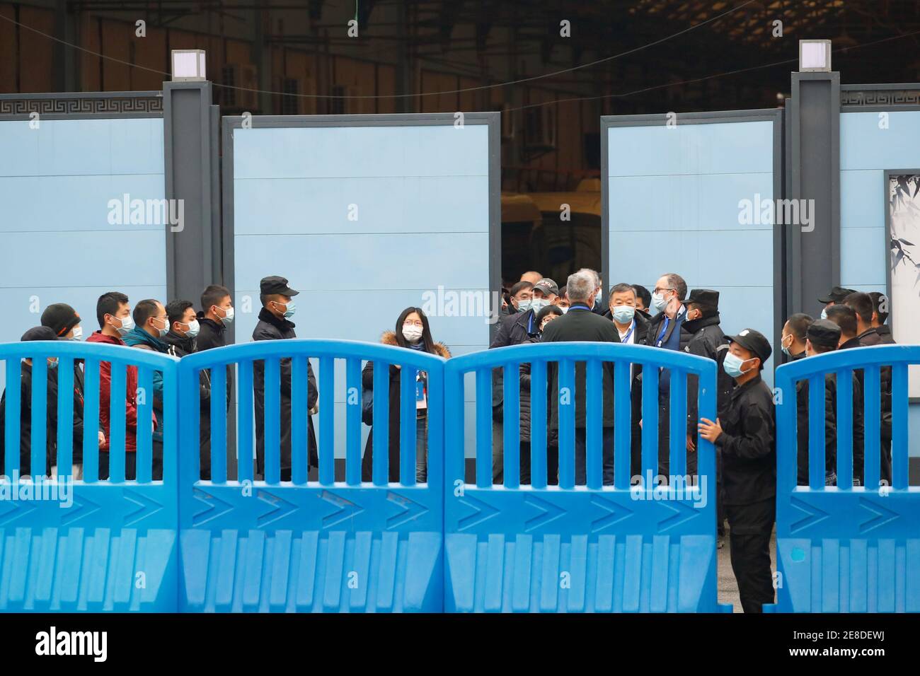 Security members keep watch as members of the World Health Organization (WHO) team tasked with investigating the origins of the coronavirus disease (COVID-19) visit Huanan seafood market in Wuhan, Hubei province, China January 31, 2021. REUTERS/Thomas Peter Stock Photo