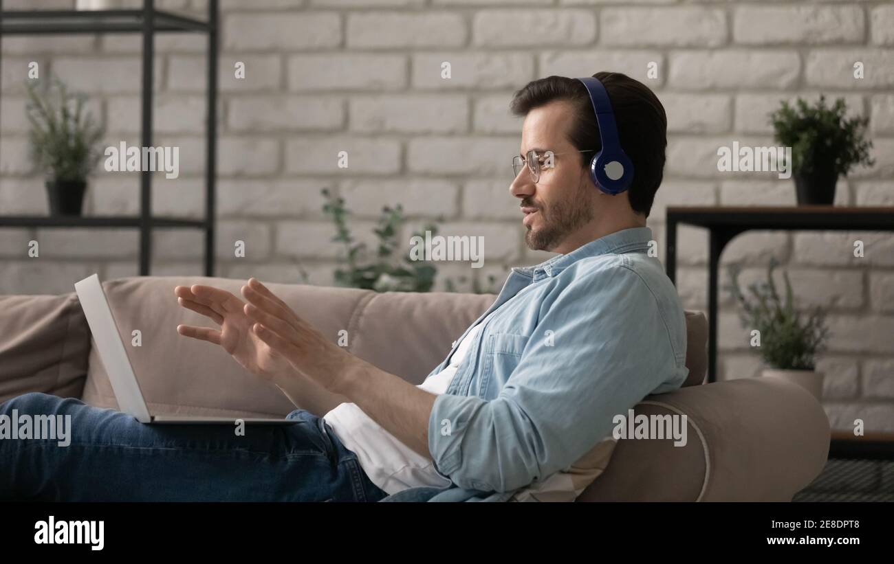 Side view man wearing headphones using laptop, making video call Stock Photo