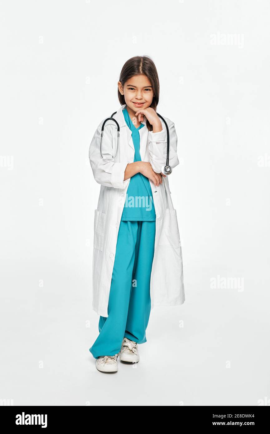 Latino little girl wearing a doctor coat and stethoscope, posing and looking at camera. Isolated on white Stock Photo
