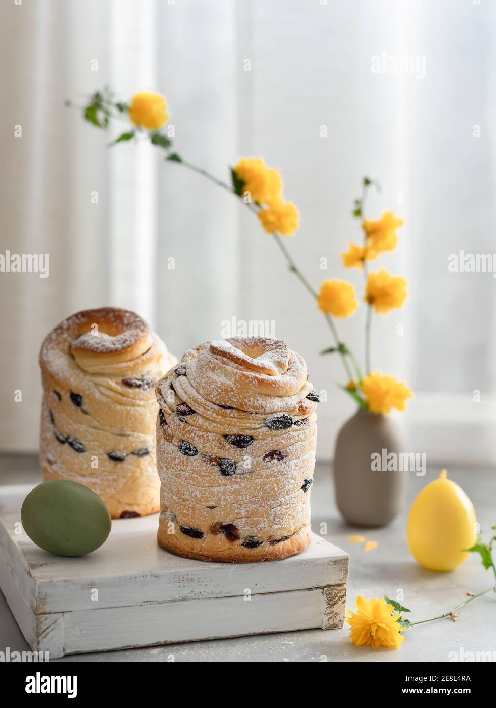 Easter layered cake Cruffin and yellow flowers background. Easter holidays composition Stock Photo