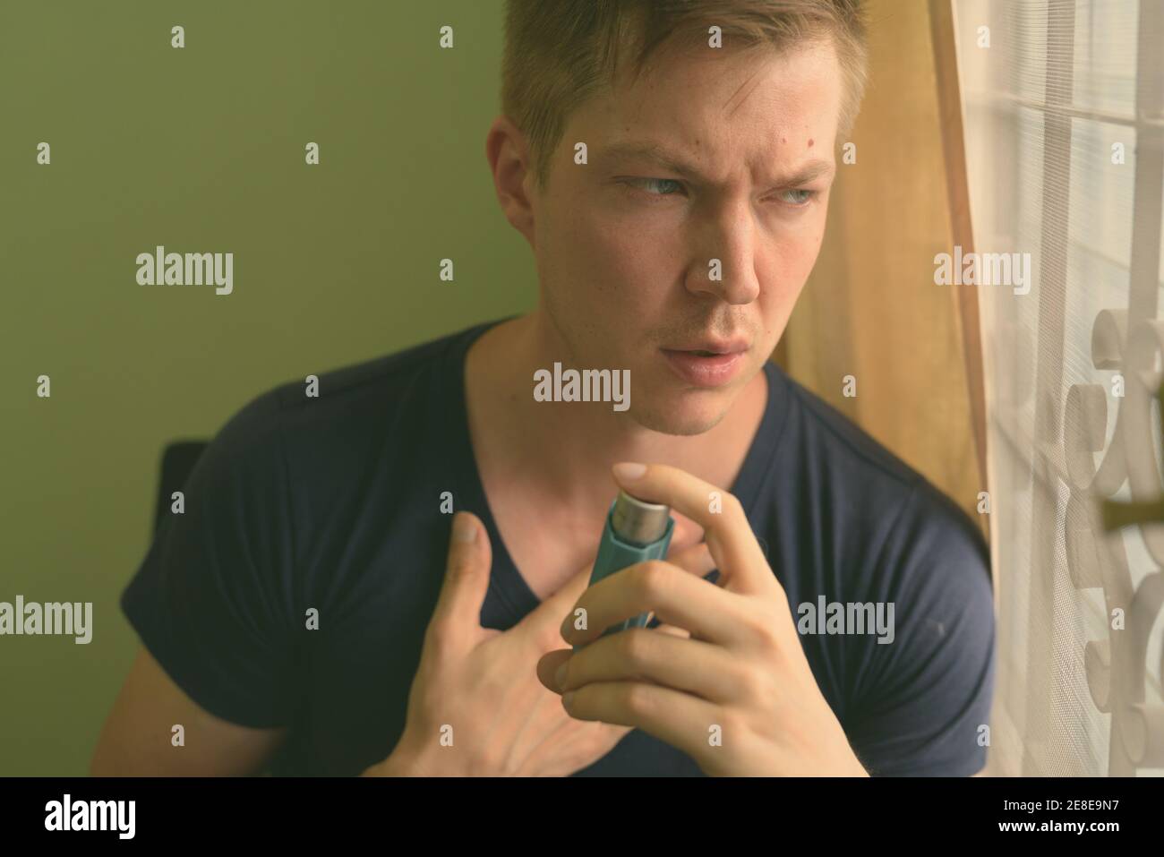 Young handsome man using asthma inhaler at home Stock Photo