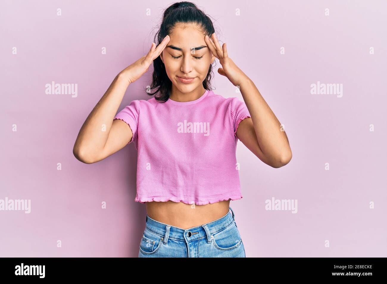 Hispanic teenager girl with dental braces wearing casual clothes with hand on head, headache