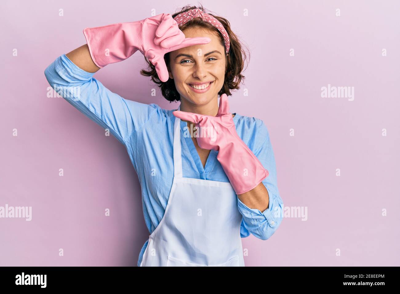 Young brunette woman wearing cleaner apron and gloves smiling making ...
