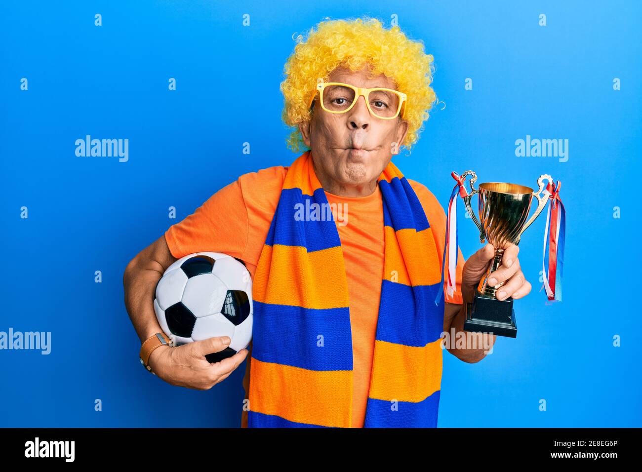 Senior hispanic man football hooligan cheering game holding ball and ...