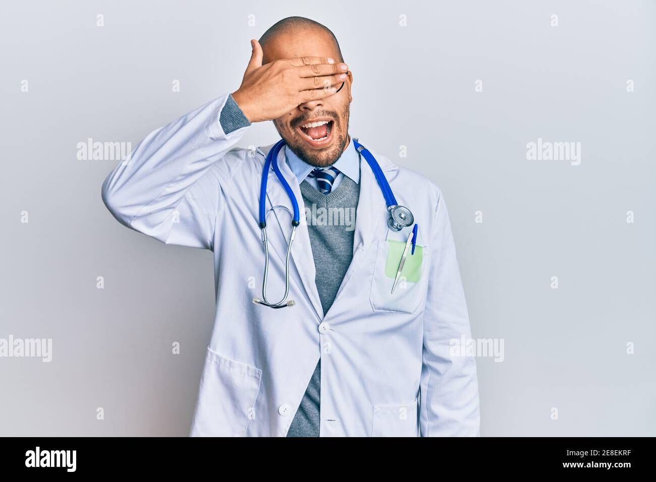 Hispanic adult man wearing doctor uniform and stethoscope smiling and