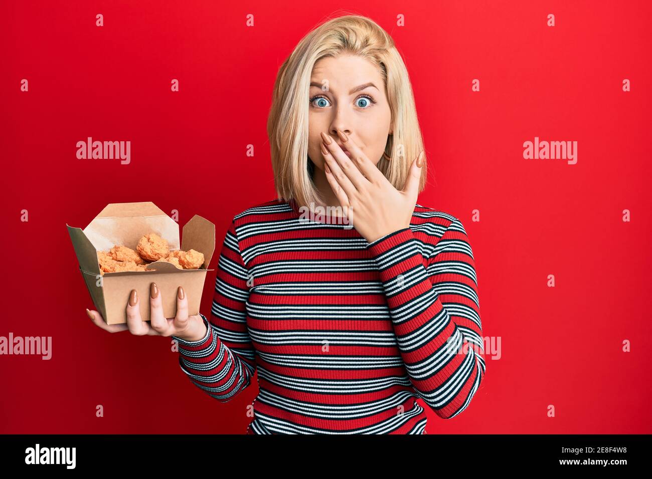 Frying Afraid Young blonde woman eating fried chicken covering mouth with hand ...