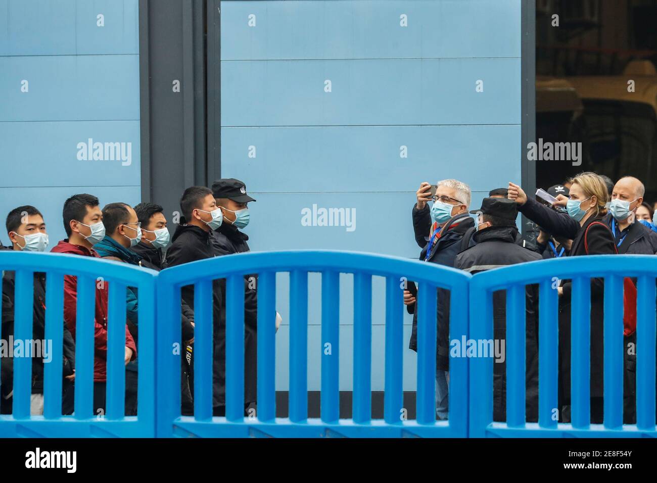Security personnel keep watch as members of the World Health Organization (WHO) team tasked with investigating the origins of the coronavirus disease (COVID-19) visit Huanan seafood market in Wuhan, Hubei province, China January 31, 2021. REUTERS/Thomas Peter Stock Photo