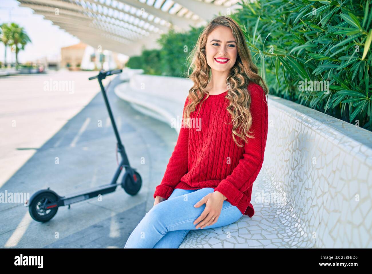 Young blonde girl smiling happy sitting on the bench at the park Stock ...