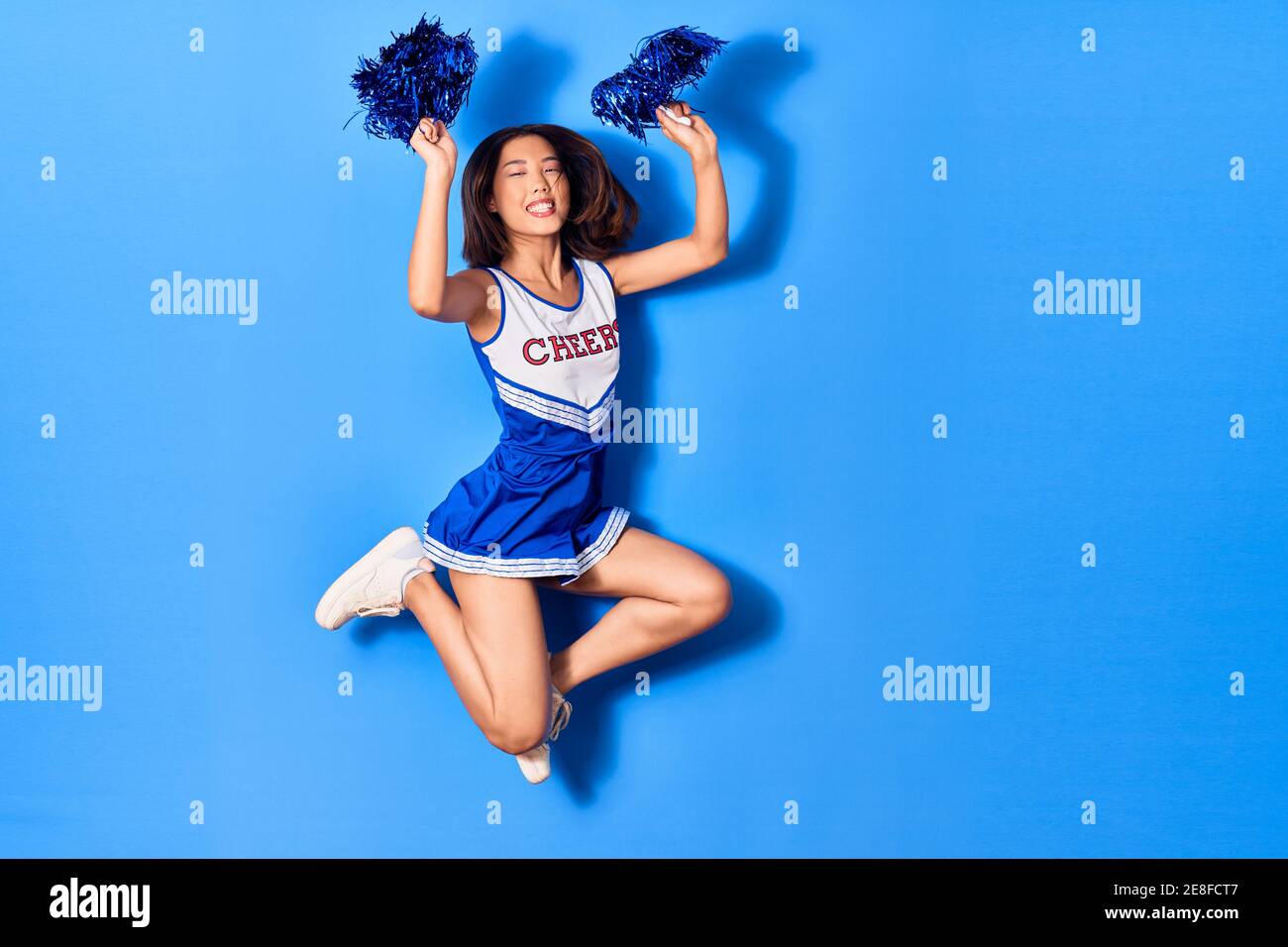 Young beautiful chinese girl smiling happy wearing cheerleader uniform