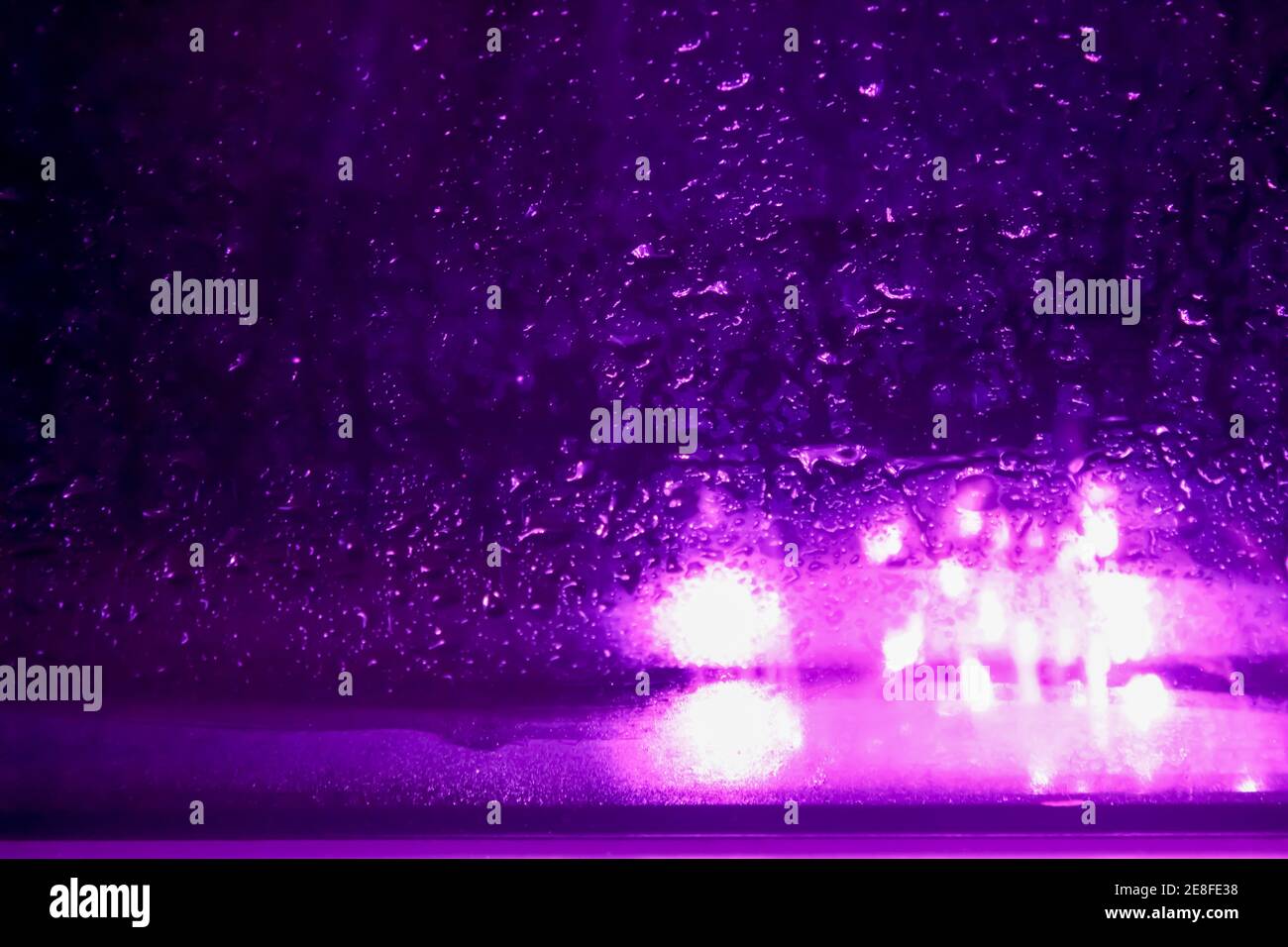 Purple light and raindrops accumulated on the window. Stock Photo