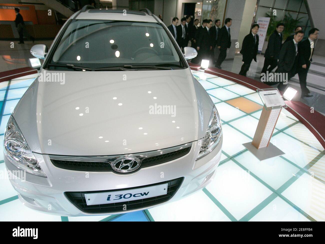 Employees of Hyundai Motor walk past its car I30 CW displayed on a lobby at the company headquarters in Seoul January 2, 2009. South Korean automakers' combined sales in December fell from a year ago, data showed on Friday, adding more concerns over the slowing world's car demand on a global recession and the financial crisis.  REUTERS/Jo Yong-Hak (SOUTH KOREA) Stock Photo