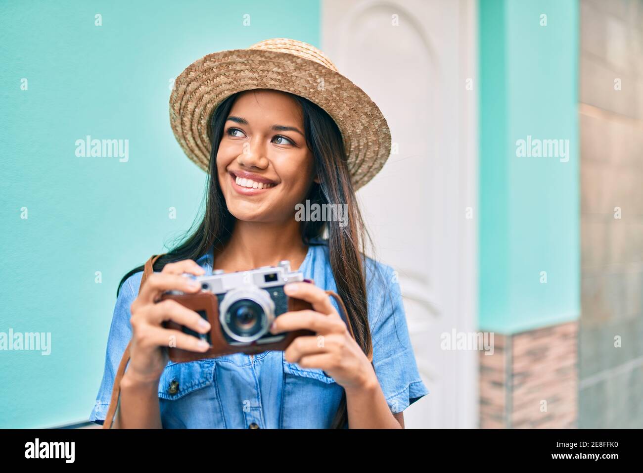 Young latin tourist girl on vacation smiling happy using vintage camera ...
