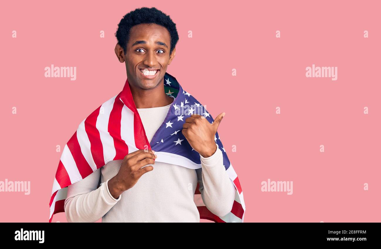 African handsome man holding united states flag pointing thumb up to ...