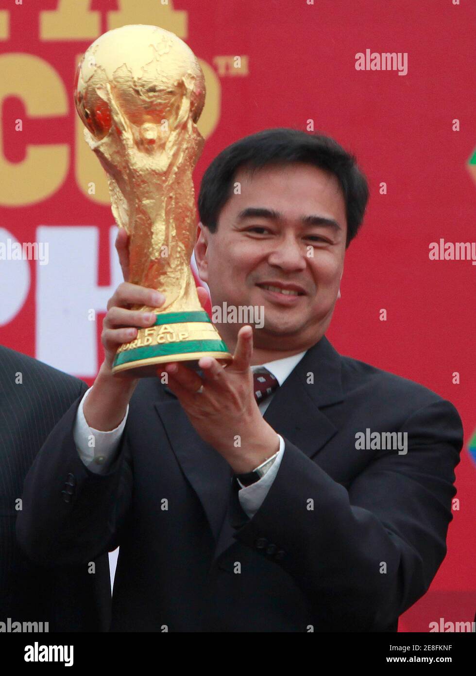 Thailand's Prime Minister Abhisit Vejjajiva holds up The FIFA World Cup trophy after it arrived at Don Muang airport in Bangkok January 21, 2010. The trophy will be in Bangkok for three days as part of its tour around the world for soccer fans. REUTERS/Chaiwat Subprasom  (THAILAND - Tags: SPORT SOCCER) Stock Photo