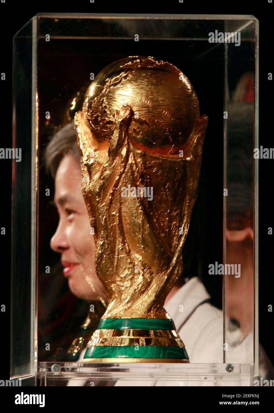 A fan poses with the FIFA World Cup trophy at a shopping mall in Bangkok January 22, 2010. The trophy will be in Bangkok for three days as part of its tour around the world for soccer fans. REUTERS/Chaiwat Subprasom  (THAILAND - Tags: SPORT SOCCER) Stock Photo
