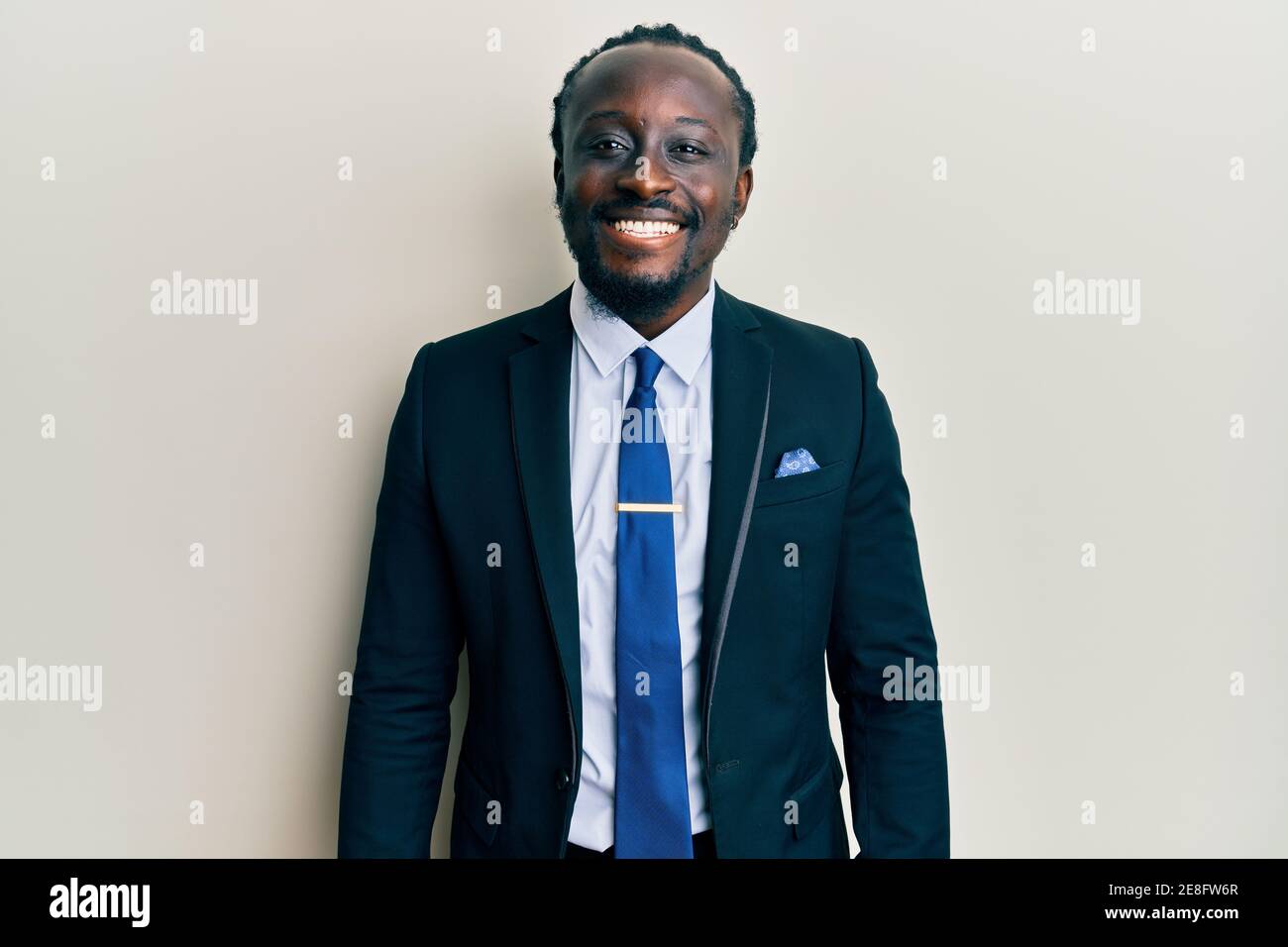 Handsome young black man wearing business suit and tie looking positive ...