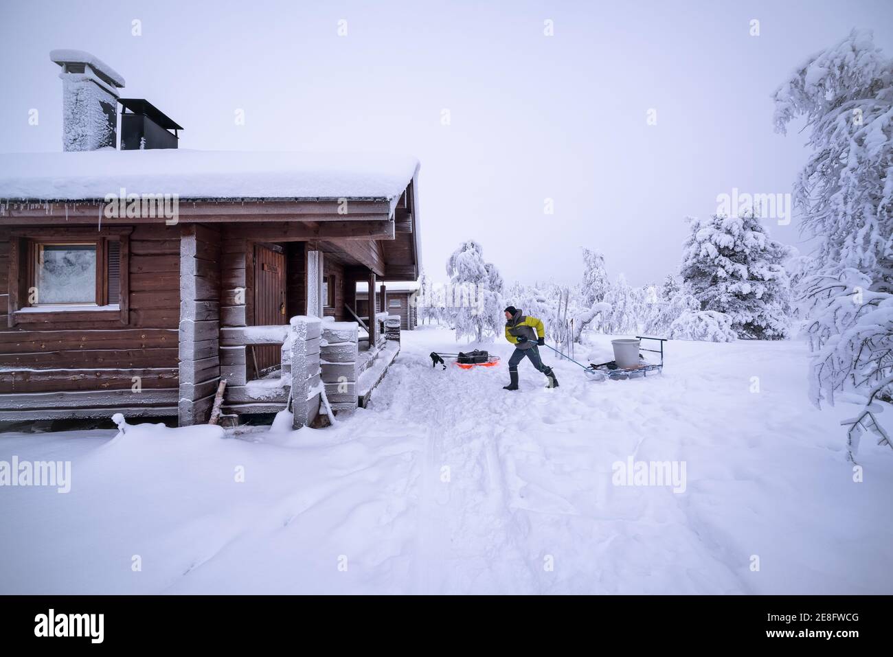 Pulling a big water bucket to the sauna at Hannukuru open wilderness hut, Enontekiö, Lapland, Finland Stock Photo