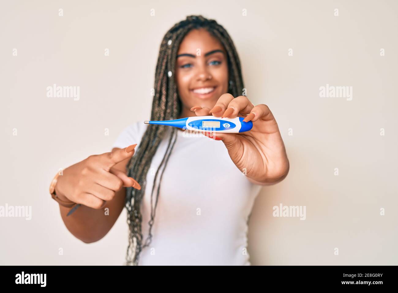 Young african american woman with braids holding thermometer smiling ...