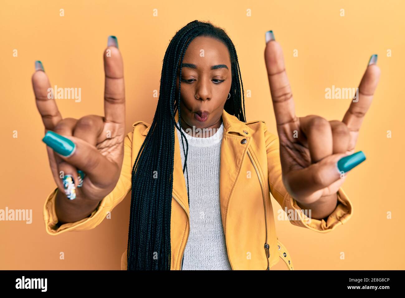 Squinting Rocks Young african american woman doing rock gesture making fish face with ...