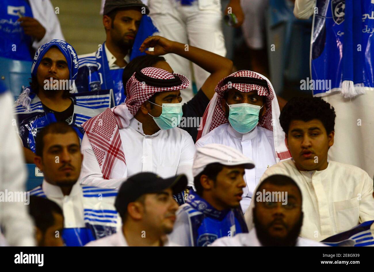Al Hilal's fans wearing face masks watch their team during their Saudi Super League qualifying soccer match against Al Nasr in Riyadh September 29, 2009. REUTERS/Fahad Shadeed     (SAUDI ARABIA SPORT SOCCER HEALTH) Stock Photo