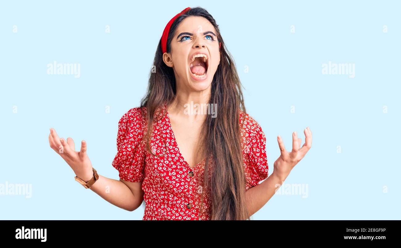 Brunette teenager girl wearing summer dress crazy and mad shouting and ...