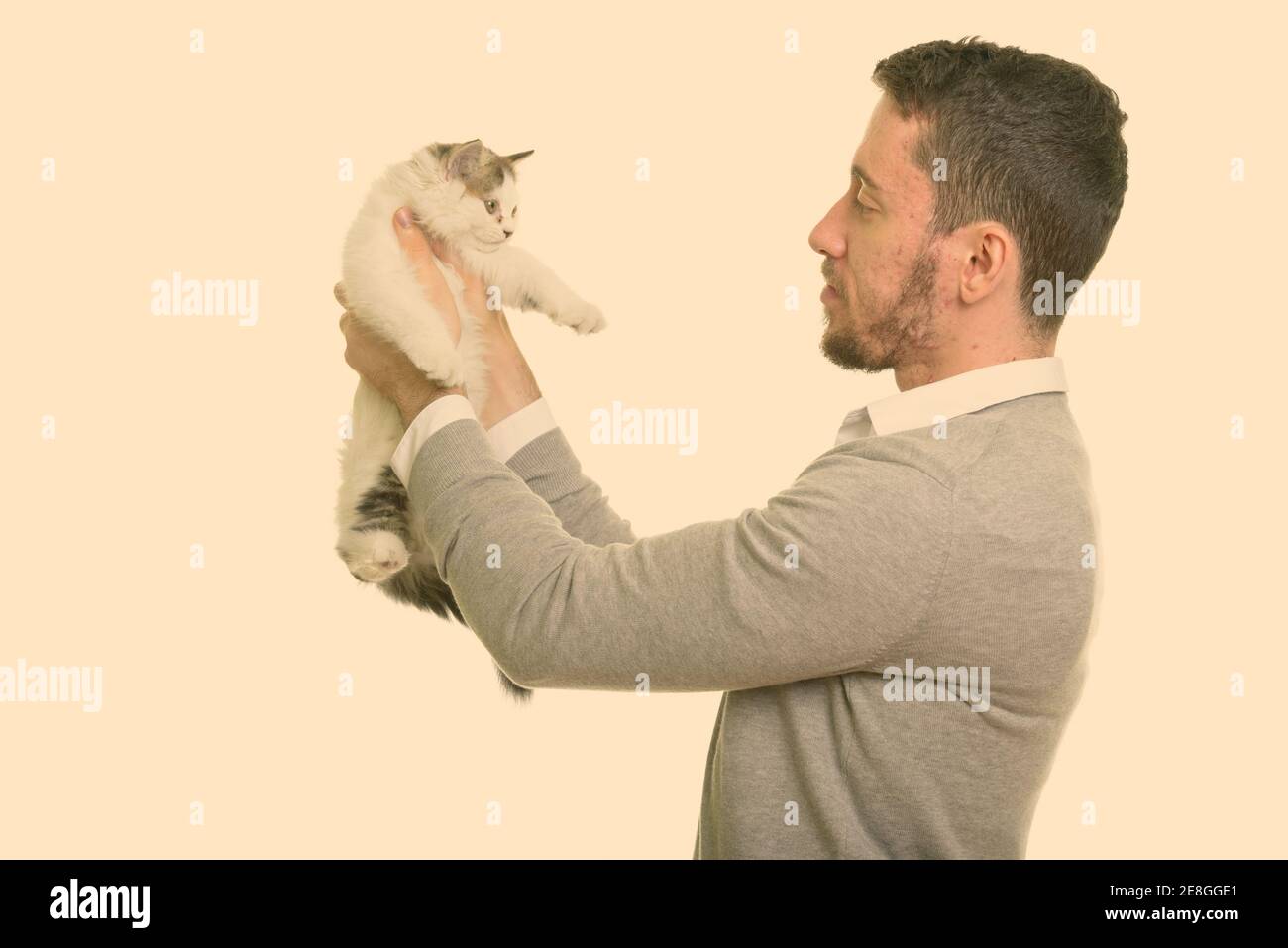 Profile view of young handsome Caucasian man holding cat Stock Photo