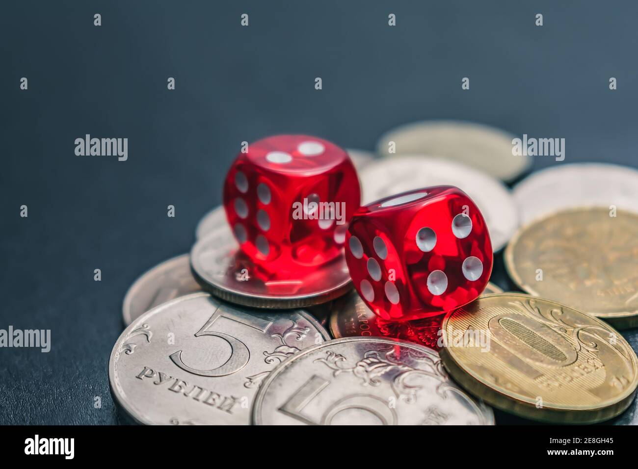 Red dice lie on different coins won at casino bets Stock Photo