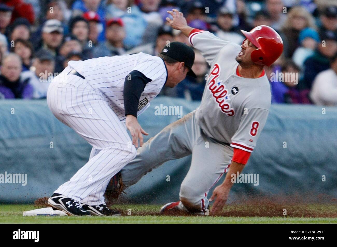 Philadelphia Phillies' Shane Victorino slides safely into third base under the tag of Colorado Rockies Garrett Atkins during the third inning of their MLB National League Division Series playoff baseball game in Denver, October 12, 2009. REUTERS/Rick Wilking (UNITED STATES SPORT BASEBALL) Stock Photo