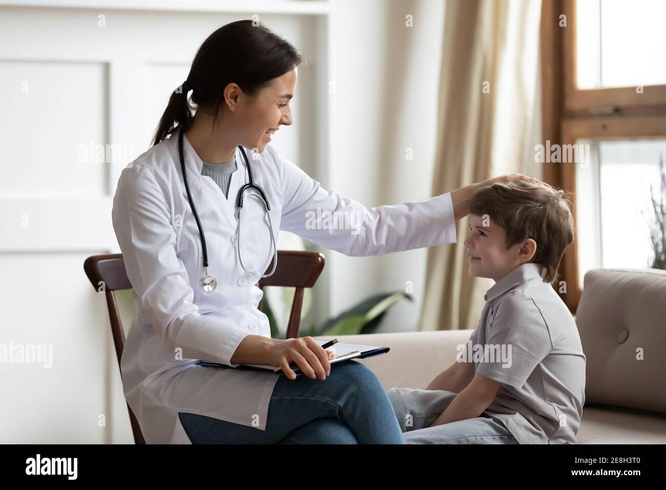 Smiling female doctor cheer small boy patient Stock Photo