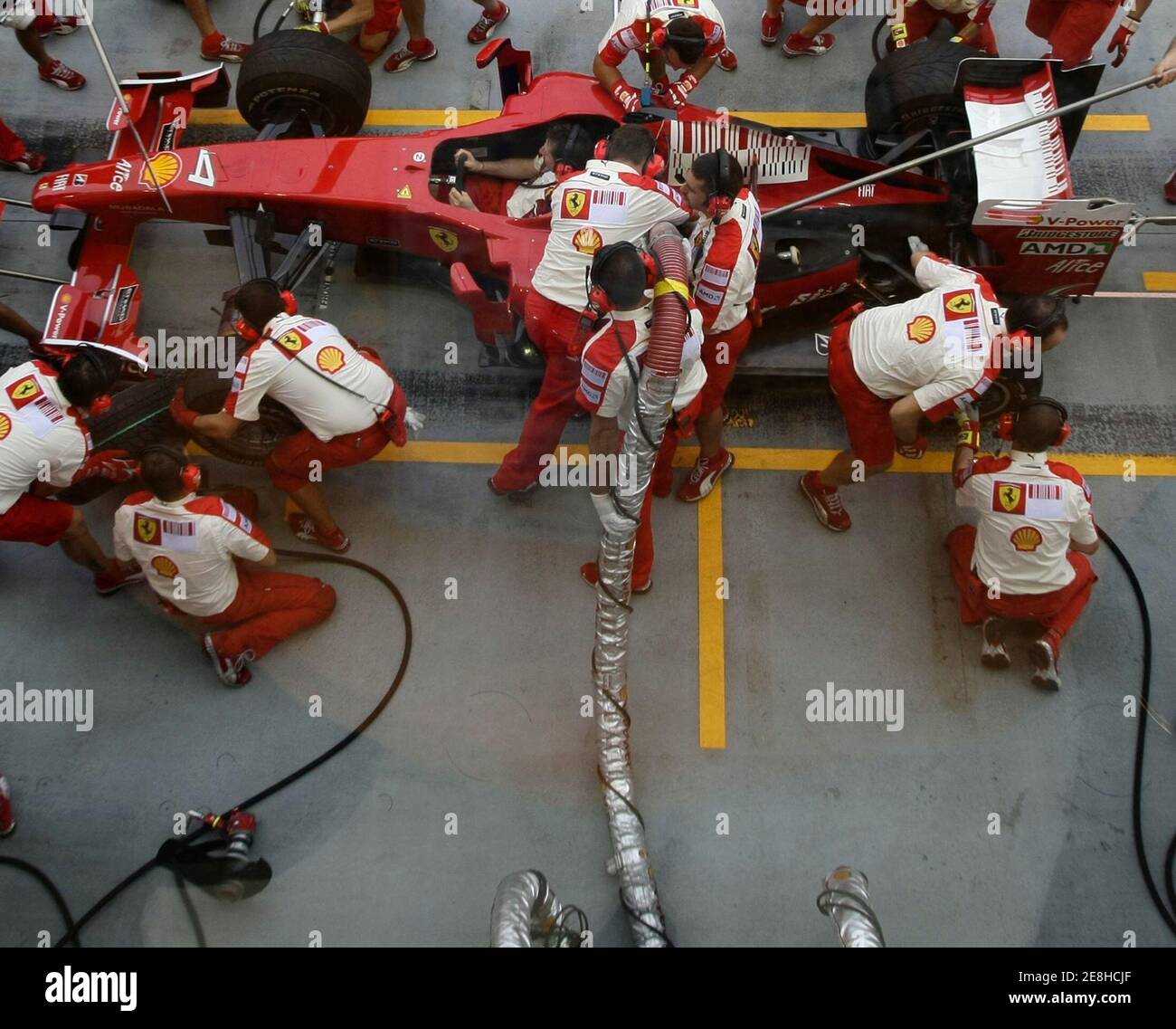 Crew members of the Ferrari Formula One team practise refuelling and pit stops prior to the start of the third practice session of the Singapore F1 Grand Prix at the Marina Bay street circuit September 26, 2009. This image was shot through glass. REUTERS/Tim Chong   (SINGAPORE SPORT MOTOR RACING) Stock Photo
